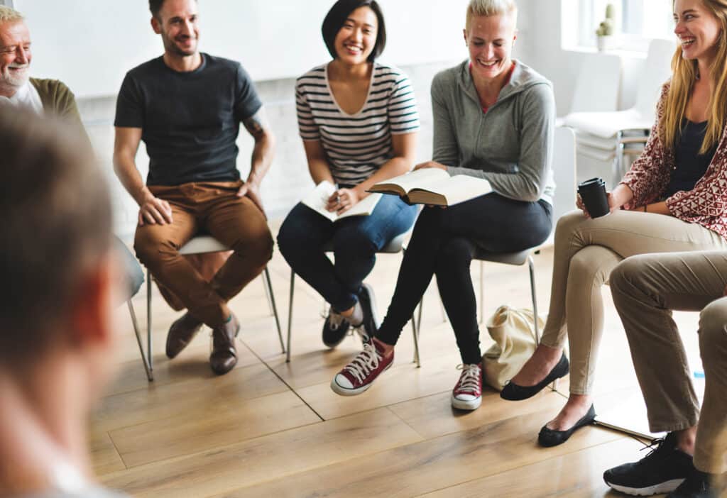 Männer und Frauen sitzen im Stuhlkreis in einem Seminar