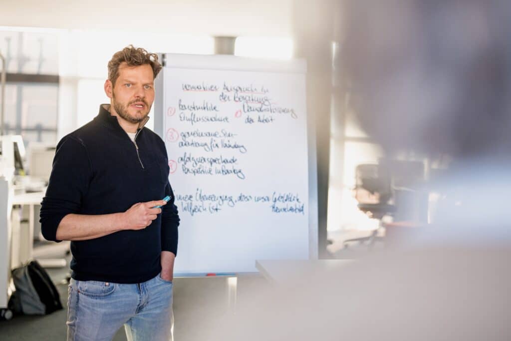 Ein CONTRACT-Mitarbeiter zeigt einem mittelständischen Unternehmen am Flipchart, wie sich die Organisation weiterentwickeln lässt