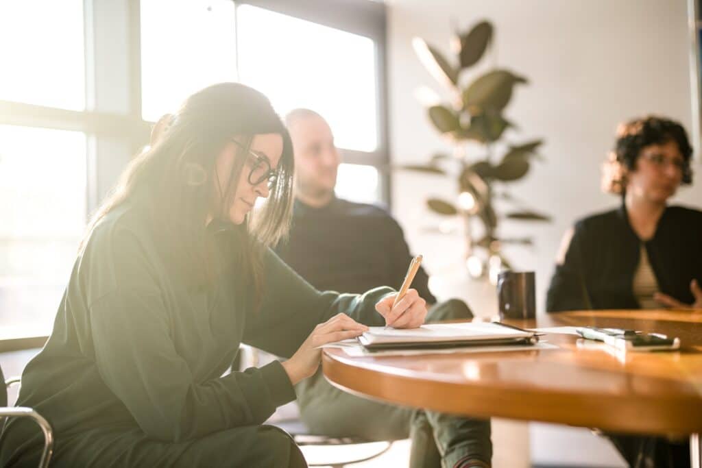 Eine CONTRACT-Beraterin macht sich in einem Projektmeeting Notizen