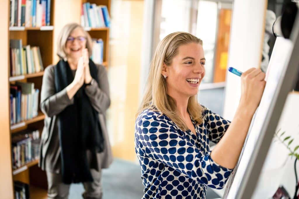 Zwei fröhliche CONTRACT-Beraterinnen schreiben am Flipchart
